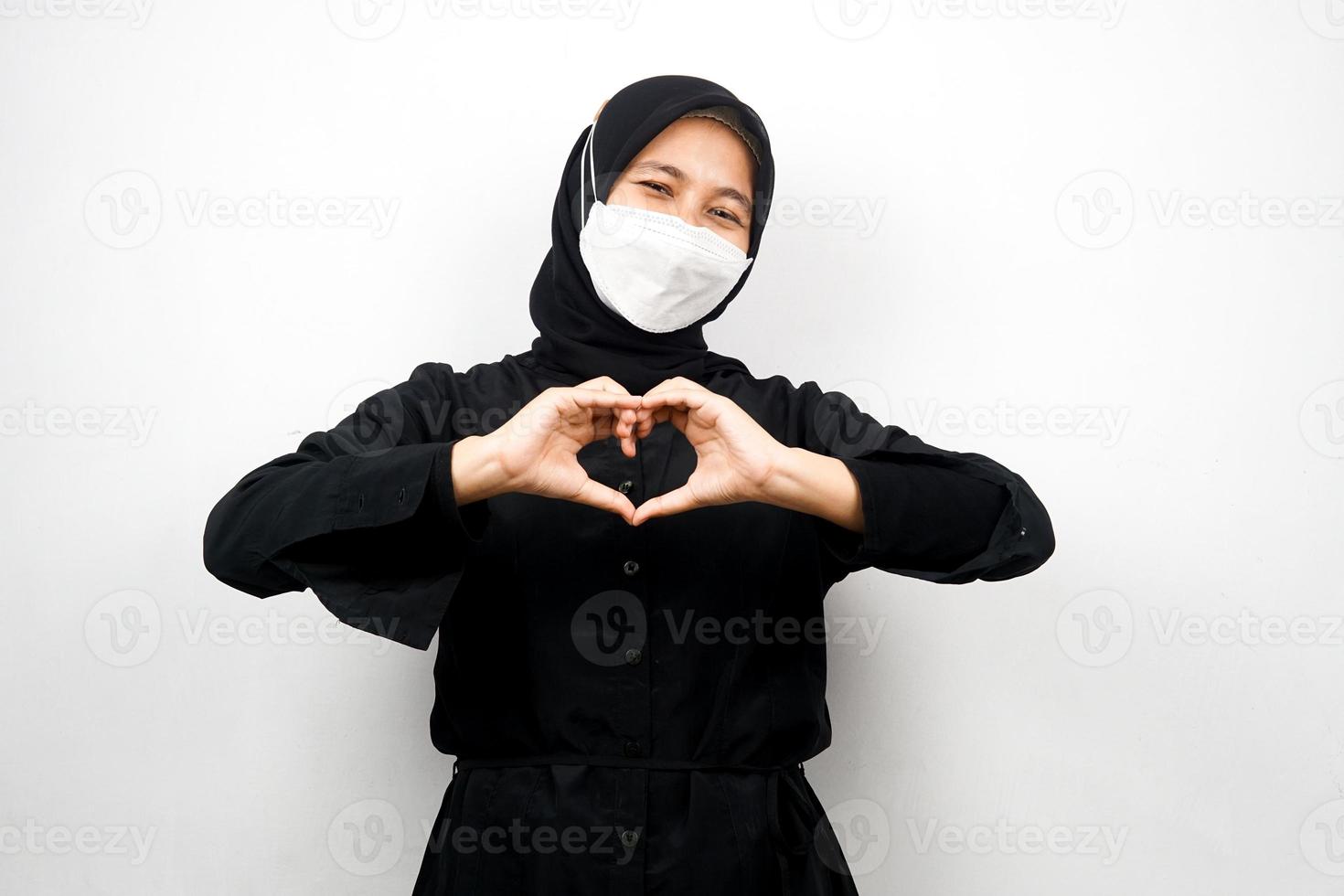 Mujer musulmana con máscara blanca, con las manos en señal de amor, afecto, feliz, aislado sobre fondo blanco. foto
