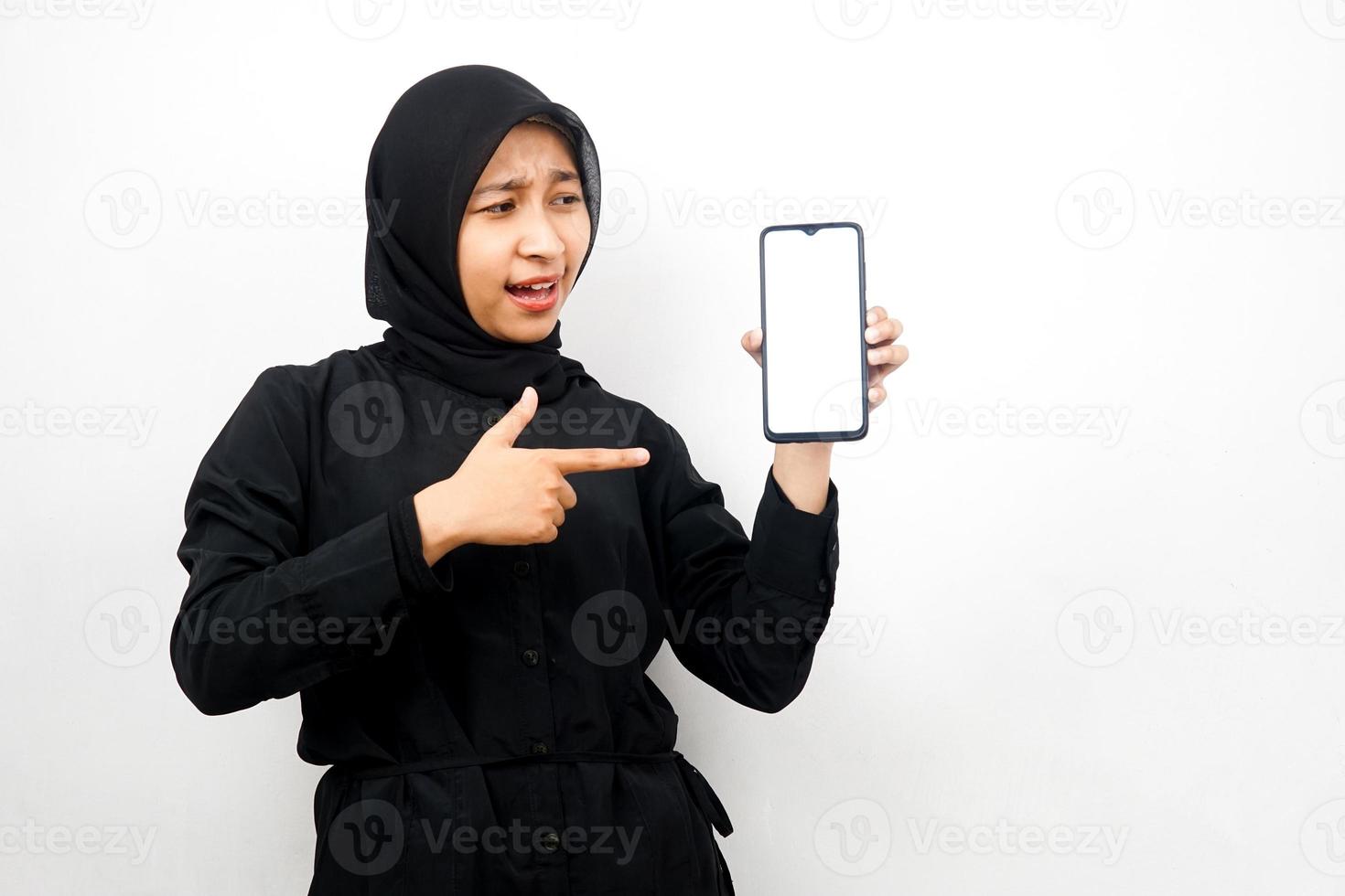 Beautiful young asian muslim woman shocked, surprised, wow expression, hand holding smartphone with white or blank screen, promoting app, promoting product, presenting something, isolated photo