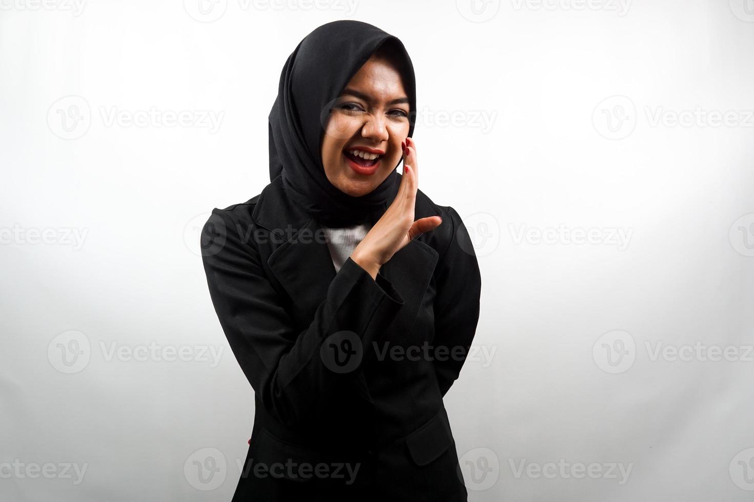 Beautiful young asian muslim business woman smiling confidently and excitedly close to camera, whispering, telling secrets, speaking quietly, silent, isolated on white background photo