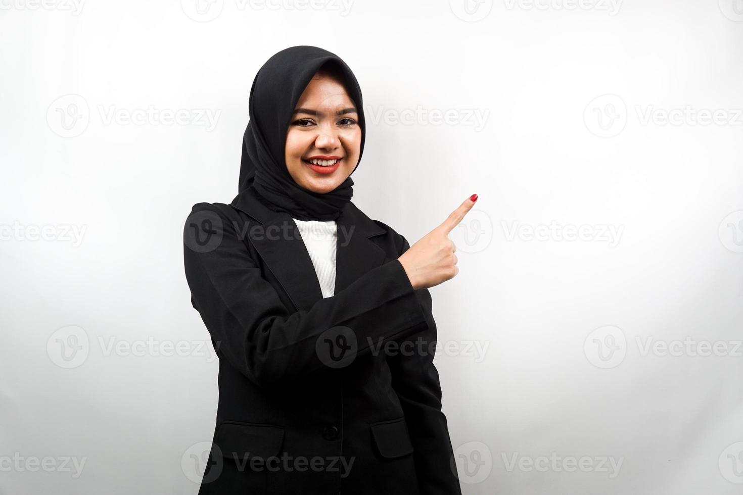 Hermosa joven mujer de negocios musulmana asiática con las manos apuntando hacia el espacio vacío presentando algo, sonriendo confiado, entusiasta, alegre, mirando a la cámara, aislado sobre fondo blanco. foto