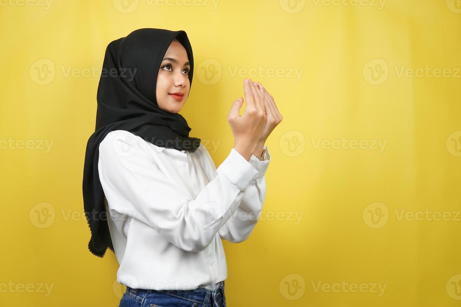 Hermosa joven musulmana asiática rezando, disculpándose, triste, sintiéndose culpable, pidiendo perdón, ayunando ramadán, islam, eid al fitr y eid adha, aislado sobre fondo amarillo foto