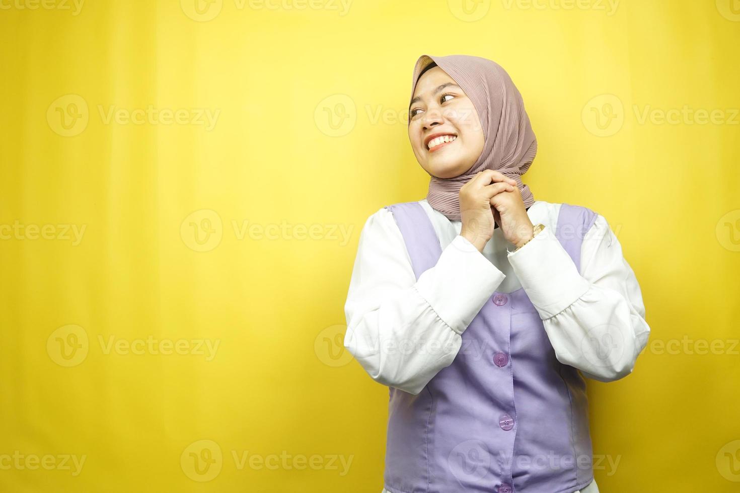 Beautiful young asian muslim woman confident and cheerful looking empty space presenting something, isolated on yellow background photo