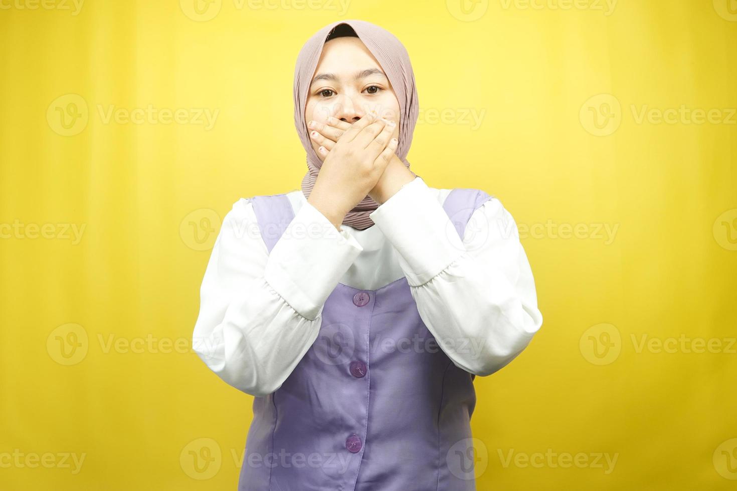 Beautiful young asian muslim woman shocked, surprised, disbelieving, getting shocking information, with hands covering mouth isolated on yellow background photo