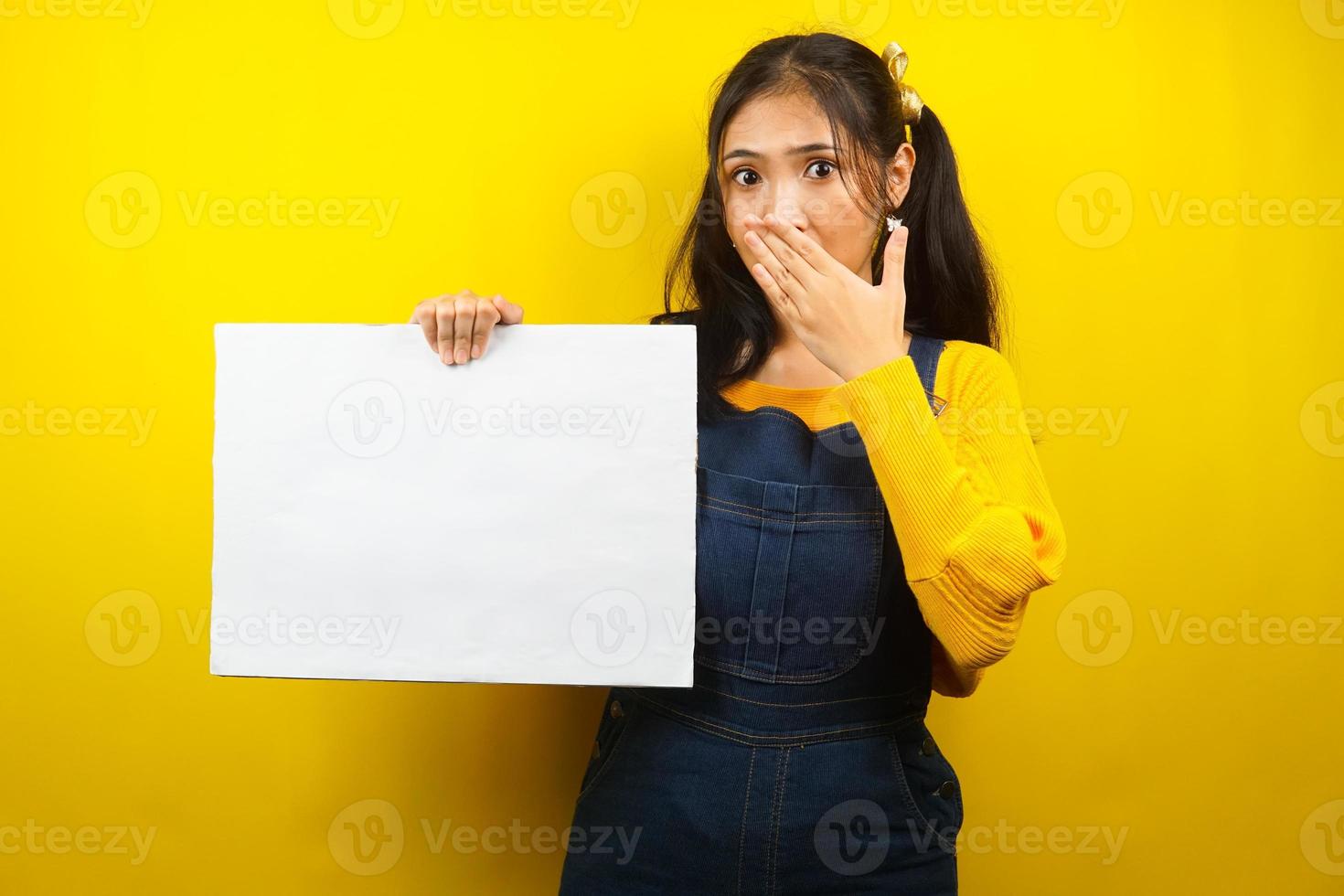 mujer joven bonita y linda sorprendida, conmocionada, guau, mano sosteniendo pancarta vacía en blanco, cartel, tablero blanco, tablero de letrero en blanco, tablero de anuncio blanco, presentando algo en el espacio de la copia, promoción foto