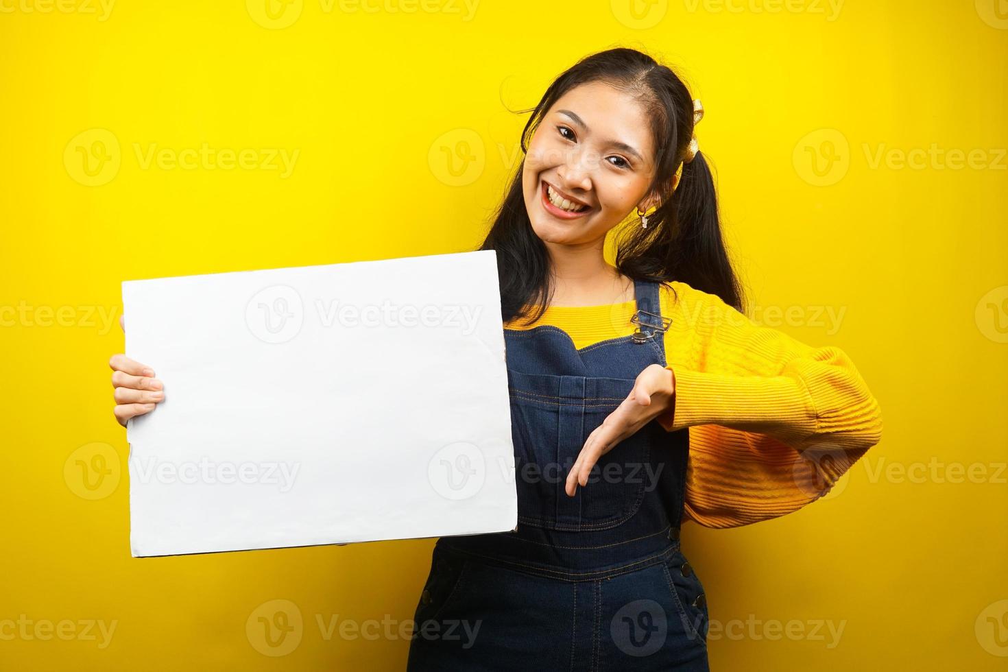 Bonita y linda mujer joven alegre sosteniendo pancarta vacía en blanco, cartel, tablero blanco, tablero de letrero en blanco, tablero de anuncio blanco, presentando algo en el espacio de la copia, promoción foto