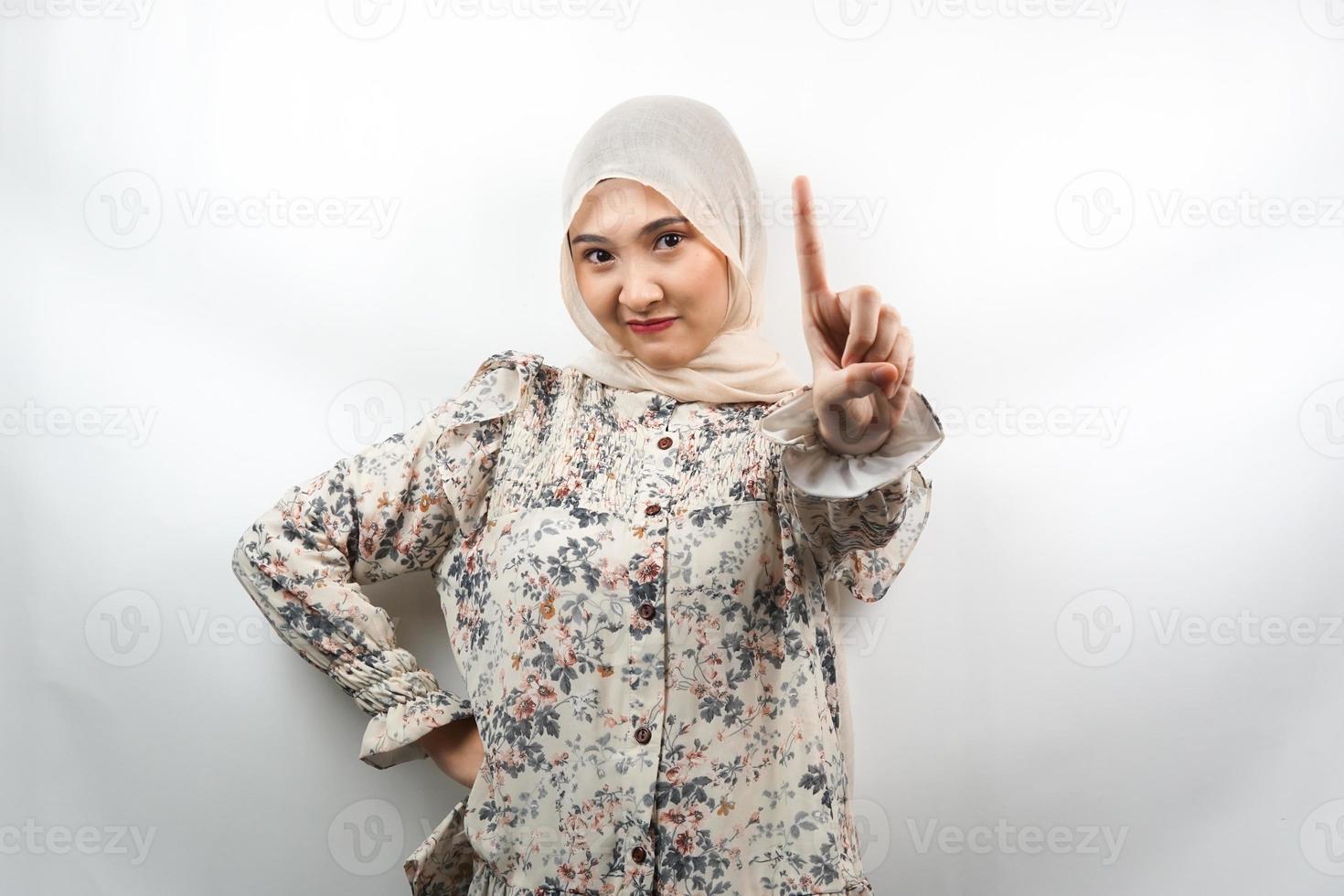 Beautiful assertive asian young muslim woman, with number one sign hand, warning sign hand to camera, isolated on white background photo