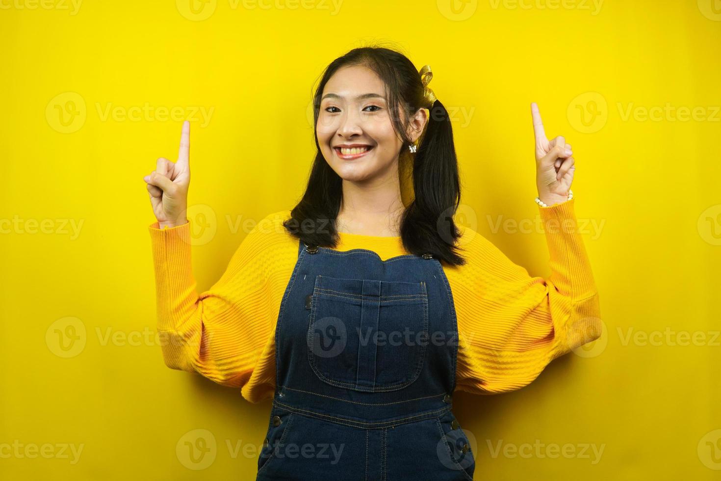 Bonita y linda mujer joven alegre, confiada, con las manos apuntando al espacio vacío presentando algo, promocionando productos, publicidad, aislado foto