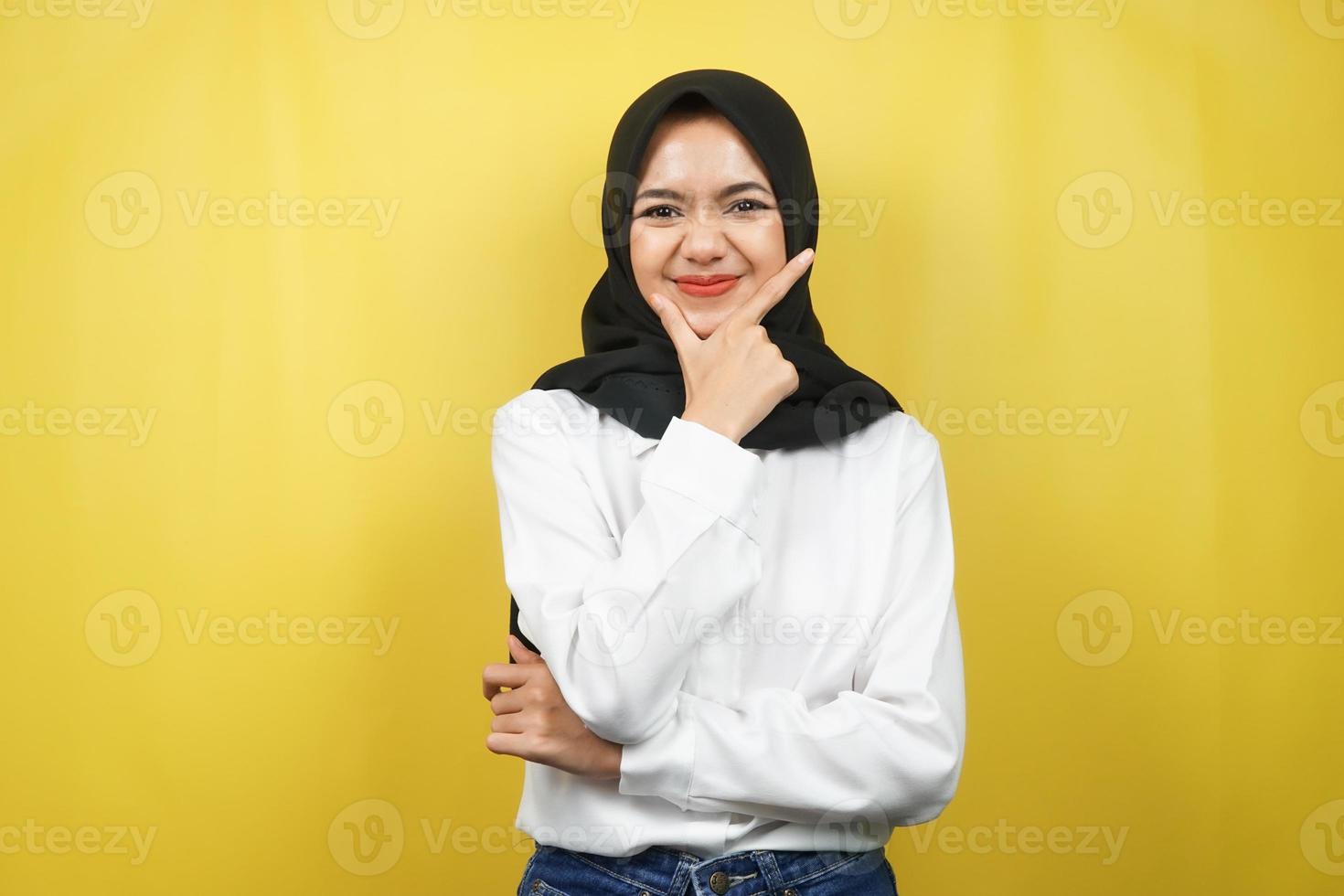 Beautiful young asian muslim woman smiling confident, enthusiastic and cheerful with hands V sign on chin isolated on yellow background photo