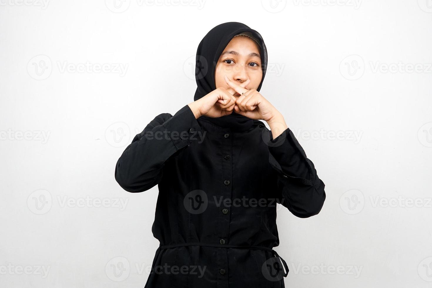 Beautiful asian young muslim woman with finger on mouth, telling to be quiet, don't make noise, lower your voice, don't talk, isolated on white background photo