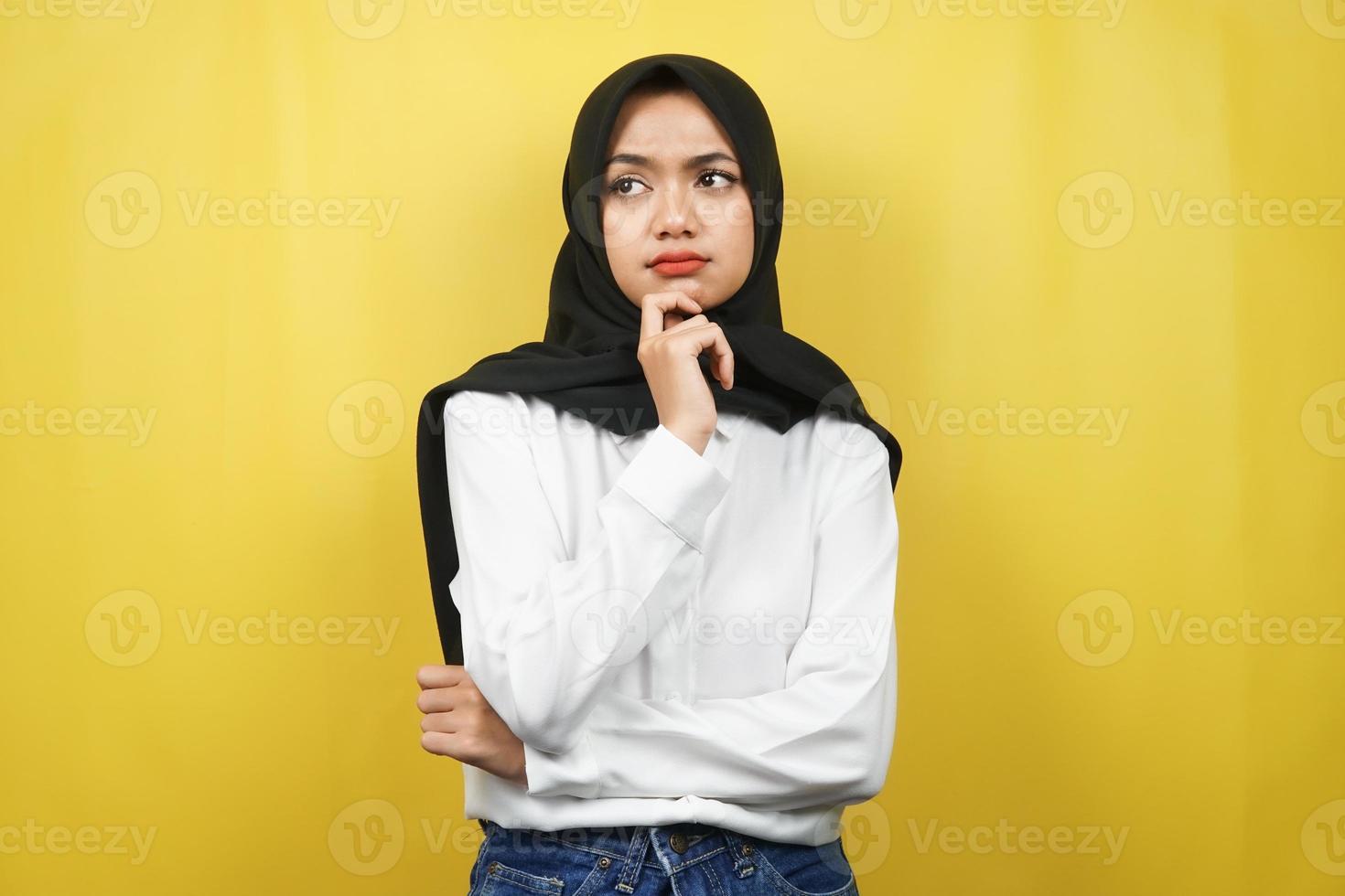 Beautiful asian young muslim woman thinking, there is a problem, feeling strange, something is wrong, looking for a solution, isolated on yellow background photo