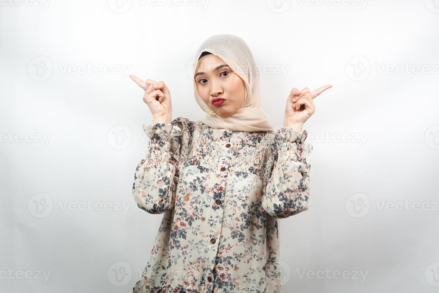 Beautiful asian young muslim woman with mouth watering, hand pointing at empty space presenting something, isolated on white background photo