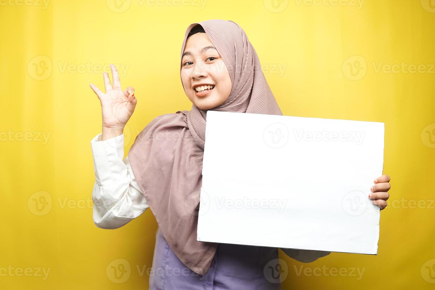 Pretty young muslim woman cheerful holding blank empty banner, placard, white board, blank sign board, white advertisement board, presenting something in copy space, promotion photo