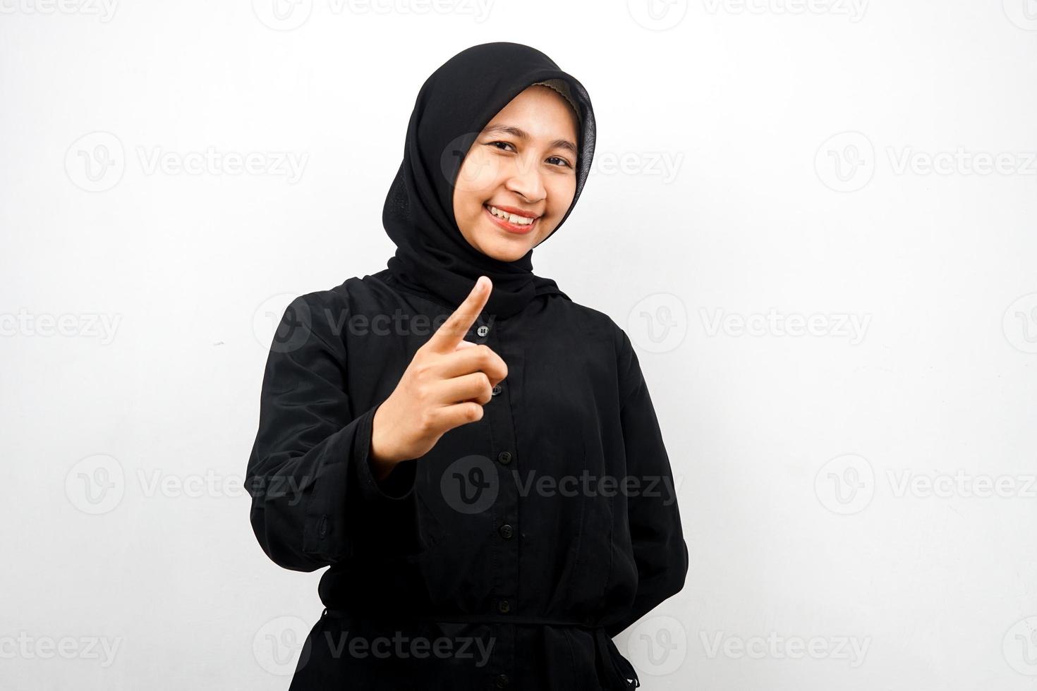 Hermosa joven musulmana asiática sonriendo confiada y alegre, con las manos apuntando a la cámara, apuntando a la audiencia, apuntando al cliente, aislado sobre fondo blanco. foto