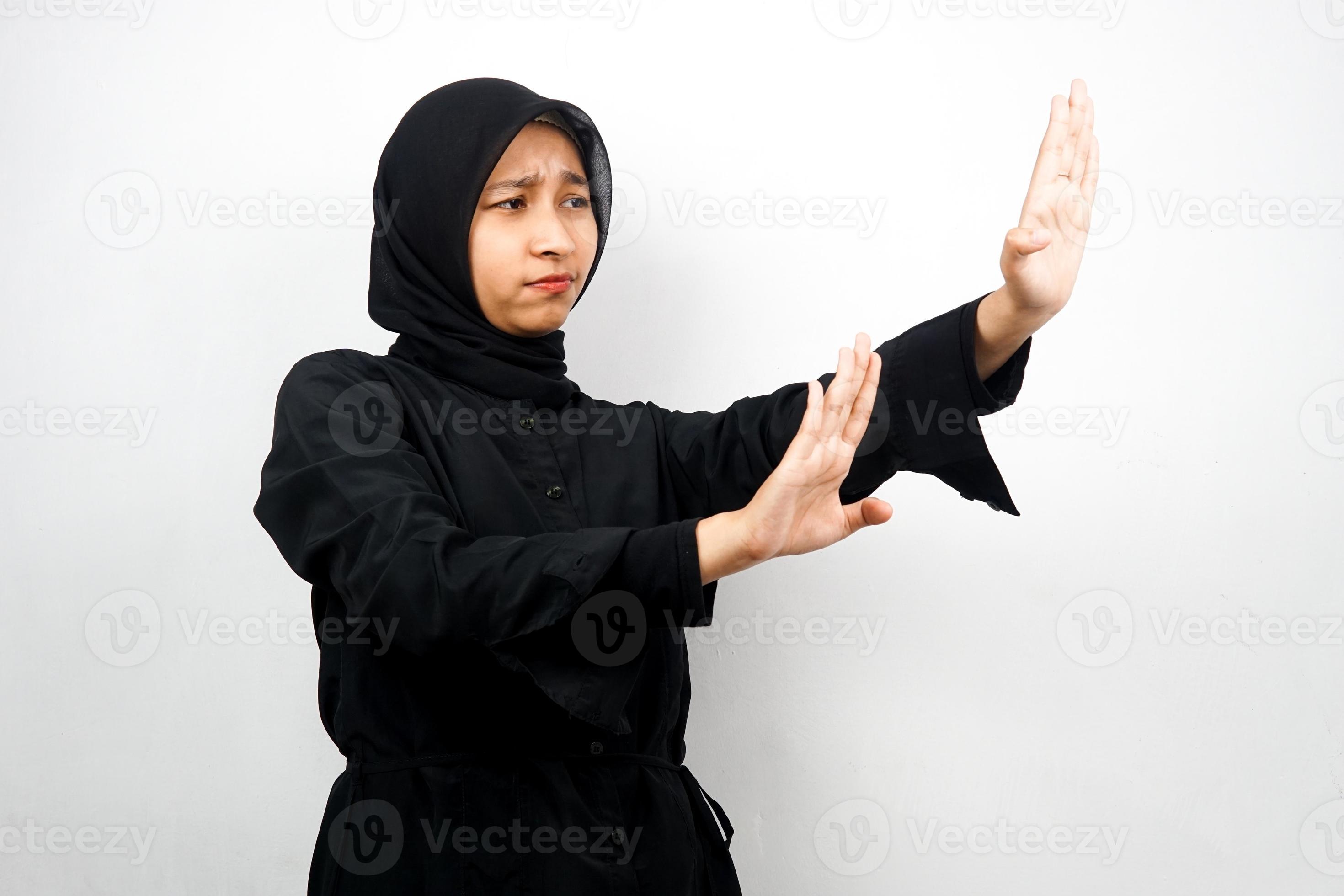 Hermosa joven musulmana asiática con la mano rechazando algo, la mano deteniendo algo, disgustando algo en el espacio vacío, aislado sobre fondo blanco. foto