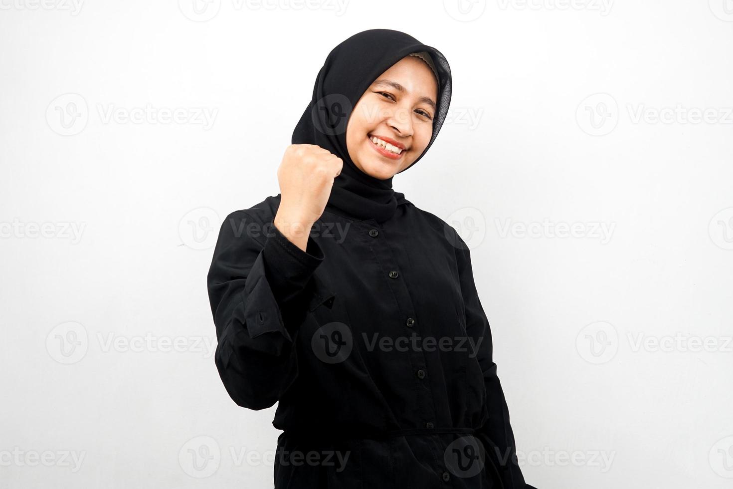 Beautiful young asian muslim woman smiling confident, enthusiastic and cheerful with hands clenched, sign of success, punching, fighting, not afraid, victory, isolated on white background photo