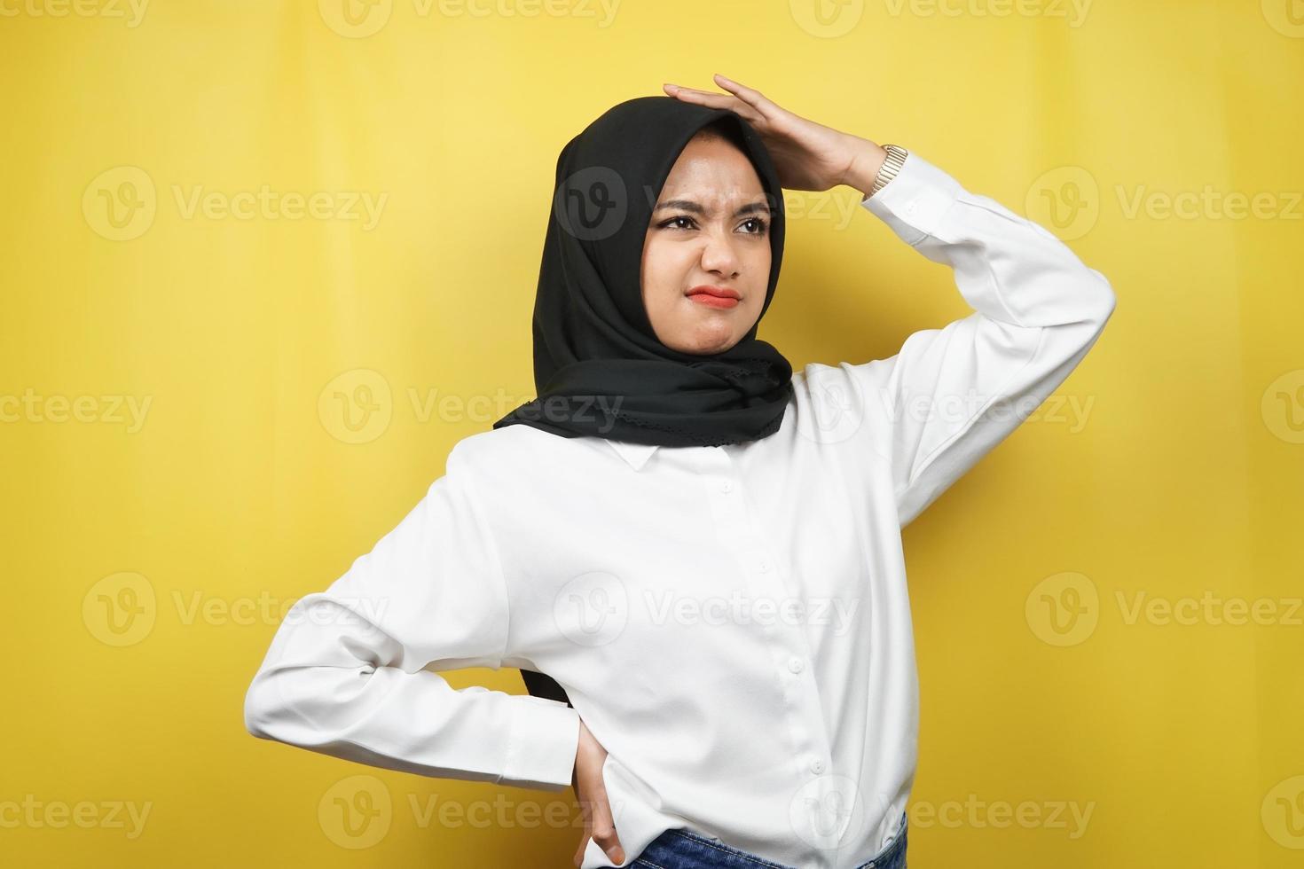 Beautiful young asian muslim woman stressed, dizzy, have a problem, feeling depressed, with hands holding head isolated on yellow background photo