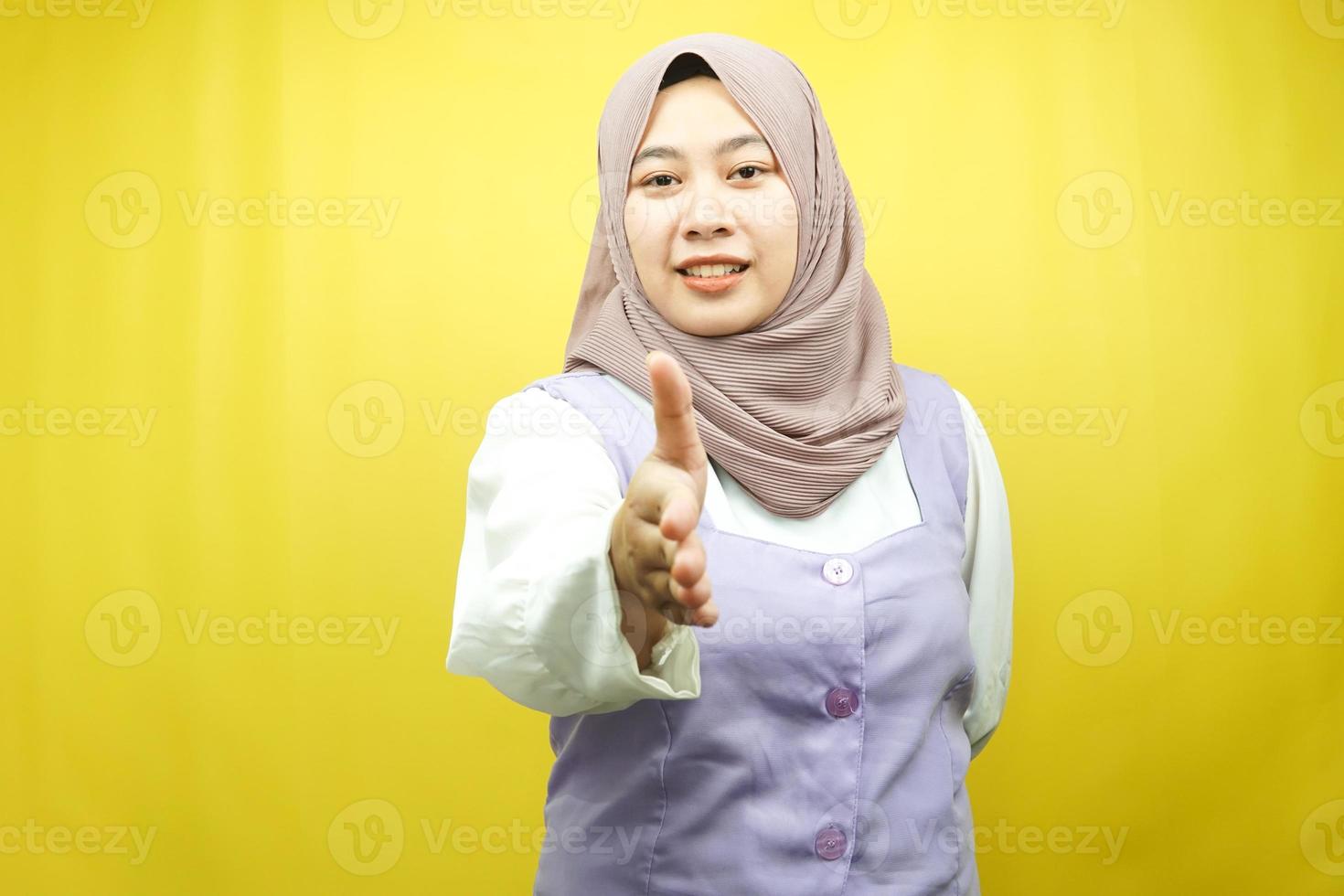 Hermosa joven musulmana asiática sonriendo con confianza, con las manos agitando la cámara, signo de cooperación con las manos, signo de acuerdo con la mano, signo de amistad, aislado sobre fondo amarillo foto