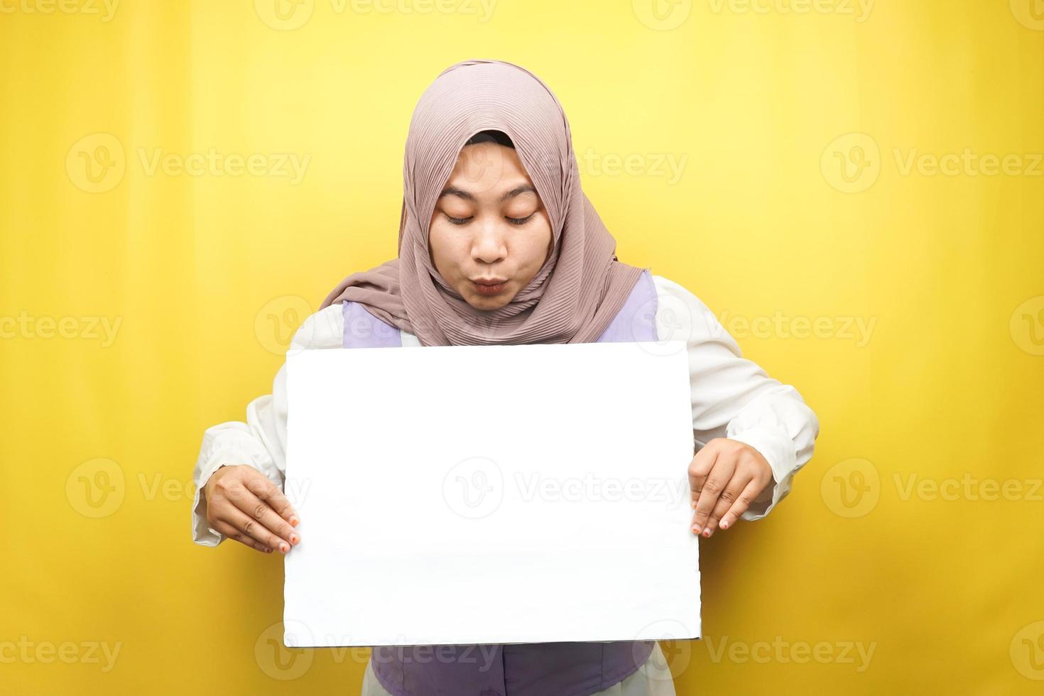 Bastante joven mujer musulmana conmocionada, sorprendida, guau, mano sosteniendo pancarta vacía en blanco, cartel, tablero blanco, tablero de letrero en blanco, tablero de anuncio blanco, presentando algo en el espacio de la copia, promoción foto