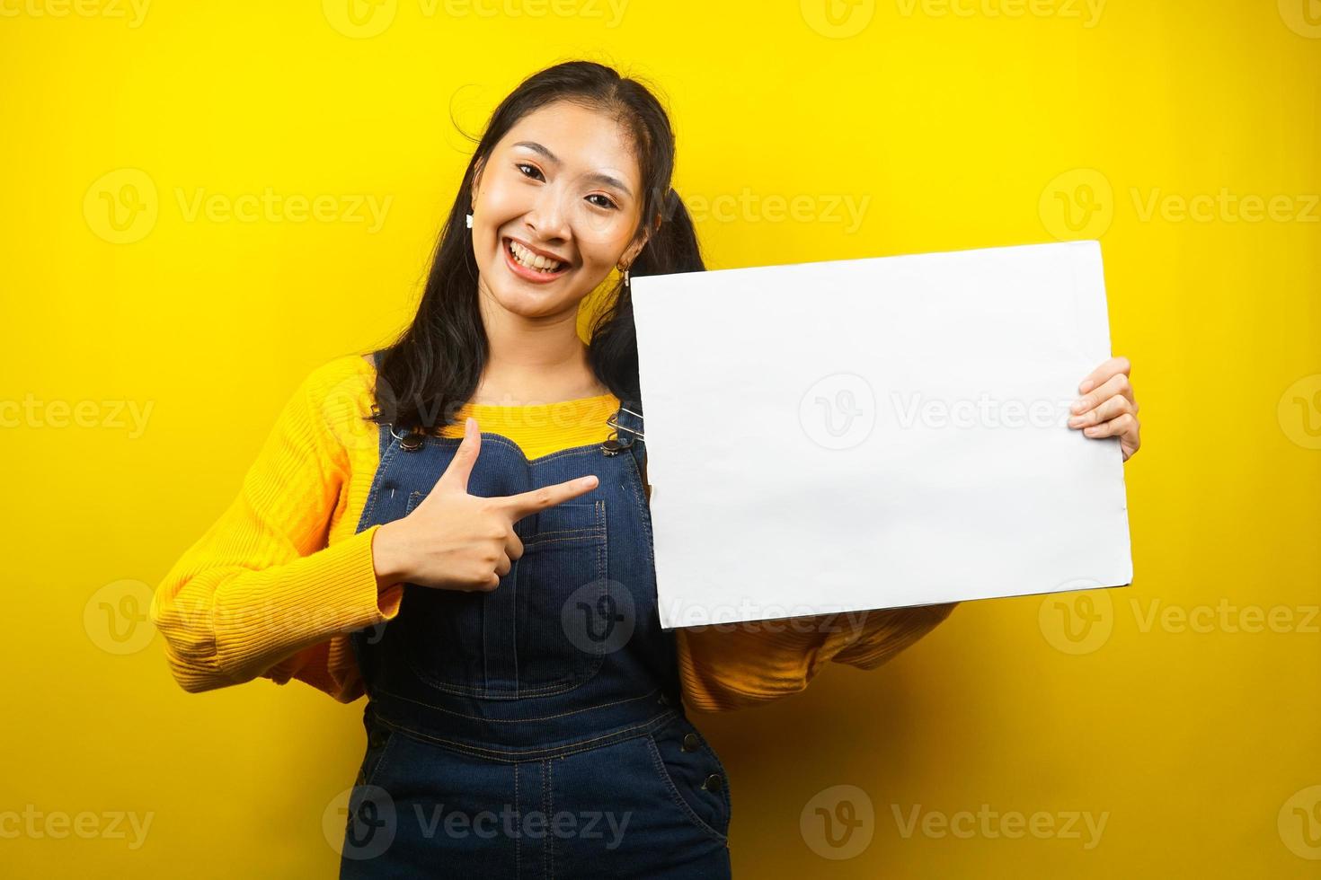 Bonita y linda mujer joven alegre sosteniendo pancarta vacía en blanco, cartel, tablero blanco, tablero de letrero en blanco, tablero de anuncio blanco, presentando algo en el espacio de la copia, promoción foto