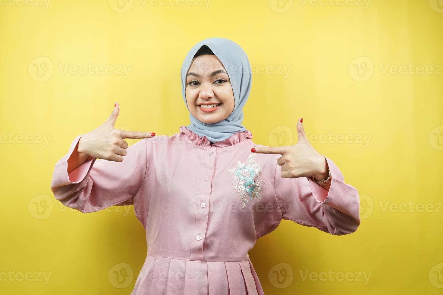 Alegre joven y bella mujer musulmana, con la mano apuntando al espacio vacío, promoviendo algo, aislado foto
