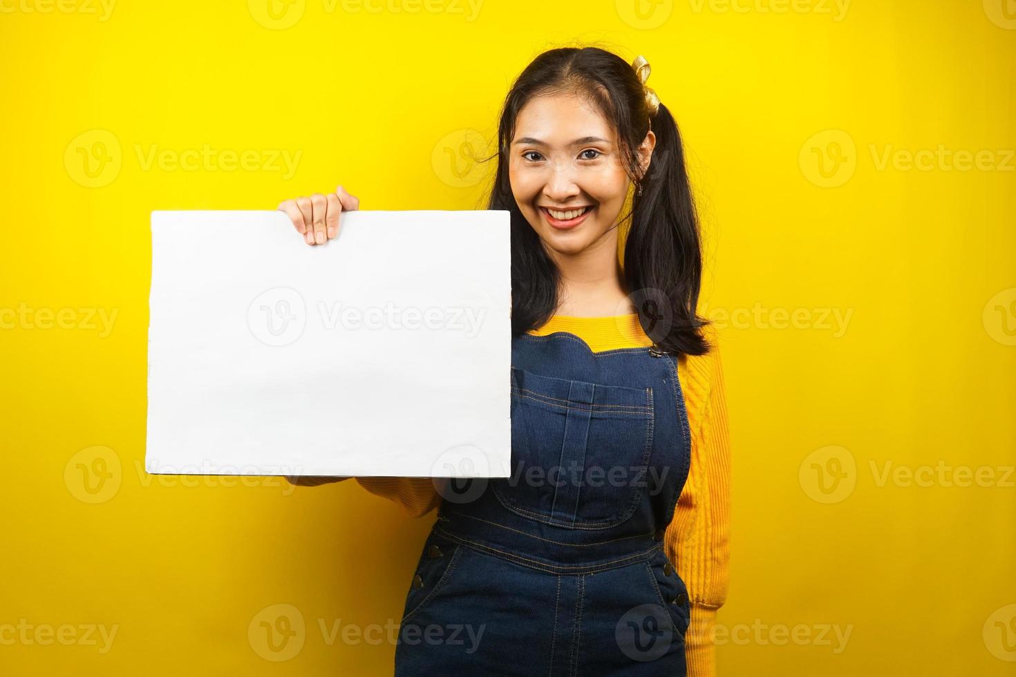 Bonita y linda mujer joven alegre sosteniendo pancarta vacía en blanco, cartel, tablero blanco, tablero de letrero en blanco, tablero de anuncio blanco, presentando algo en el espacio de la copia, promoción foto