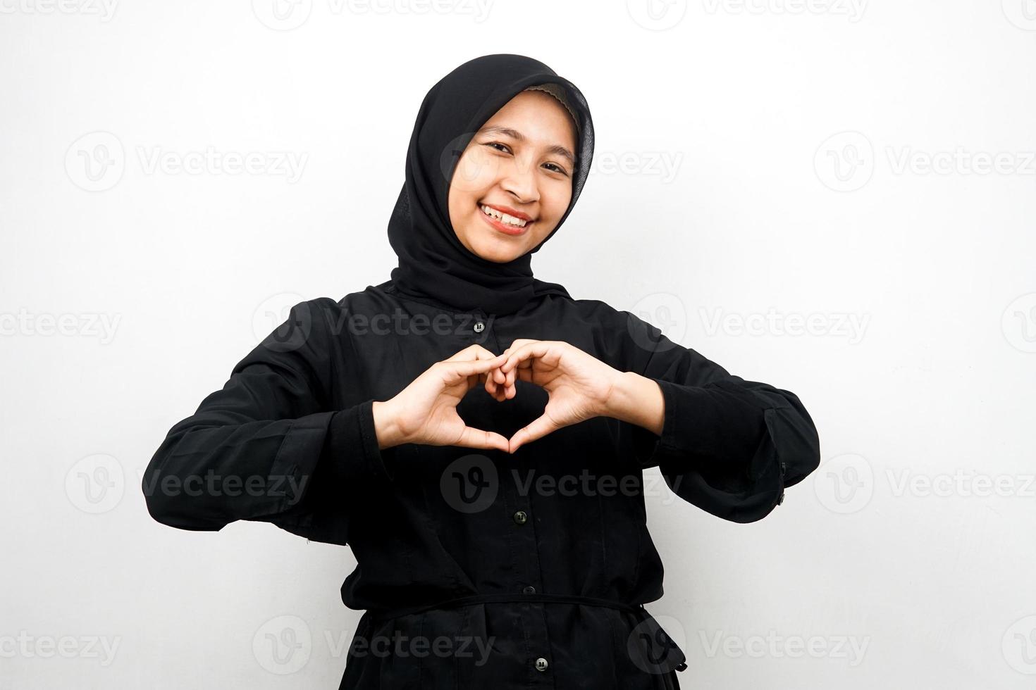 Beautiful asian young muslim woman smiling confident, enthusiastic and cheerful with hands sign of love, affection, happy, on chest isolated on white background photo