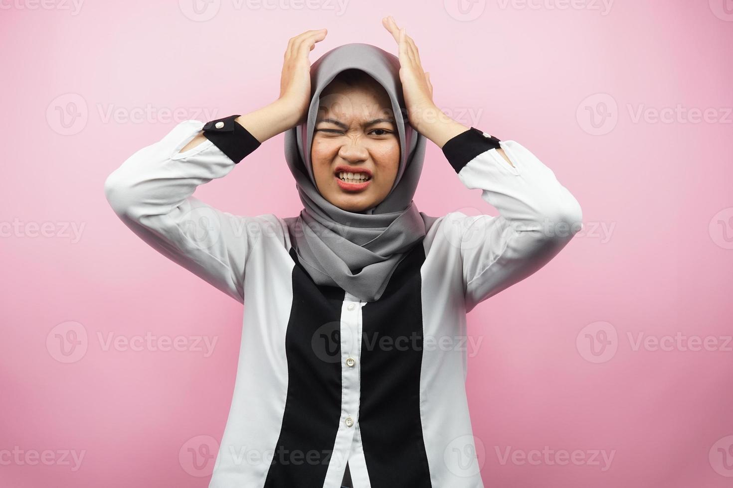 Beautiful young asian muslim woman stressed, shocked, dizzy, unhappy, many problems, want solution, with hands holding head isolated on pink background photo