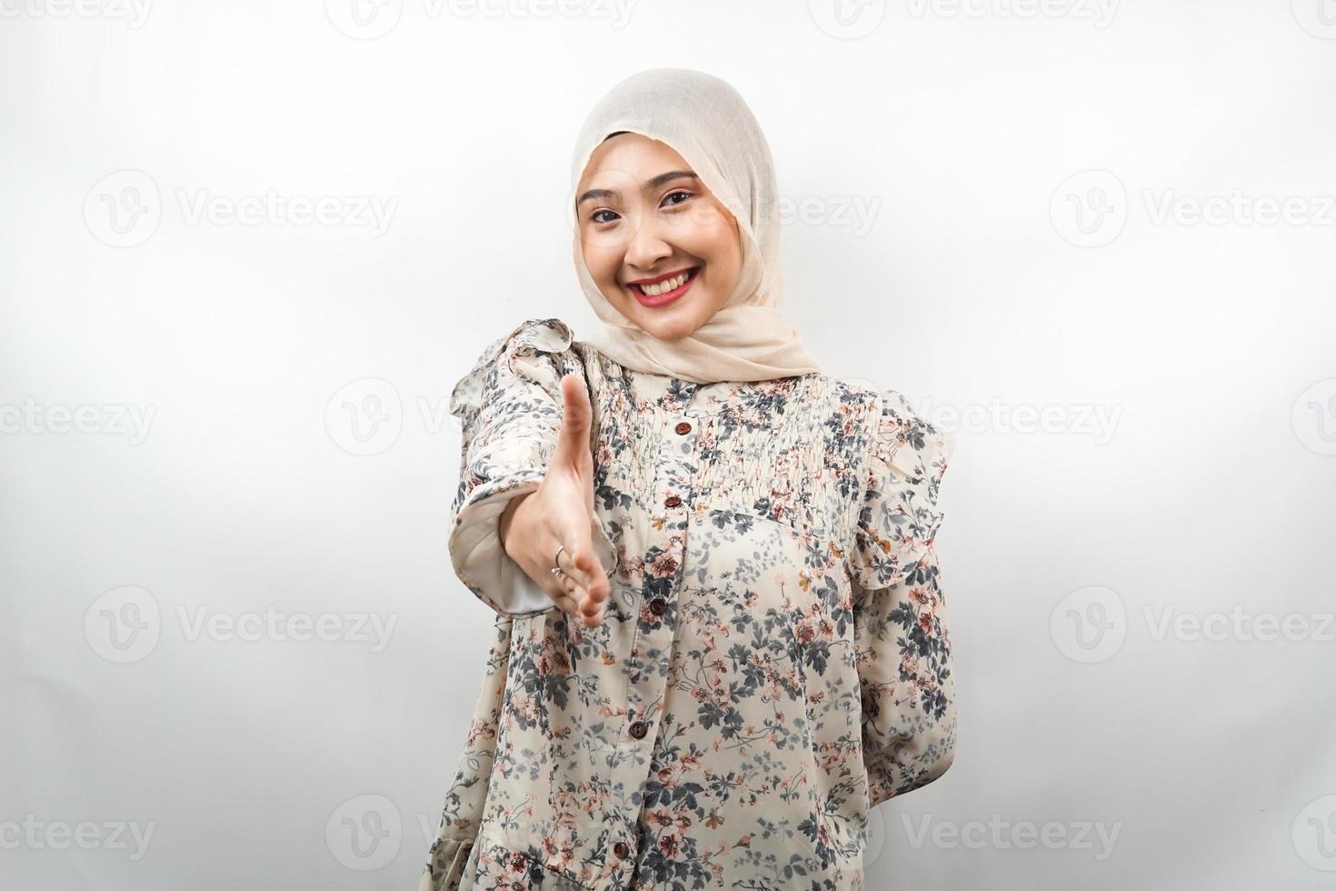 Beautiful young asian muslim woman smiling confidently, with hands shaking the camera, hands sign of cooperation, hand sign of agreement, hand sign of friendship, isolated on white background photo