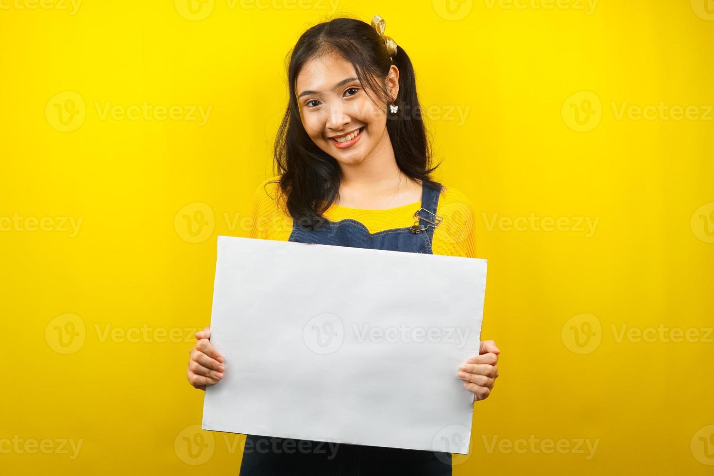 Bonita y linda mujer joven alegre sosteniendo pancarta vacía en blanco, cartel, tablero blanco, tablero de letrero en blanco, tablero de anuncio blanco, presentando algo en el espacio de la copia, promoción foto