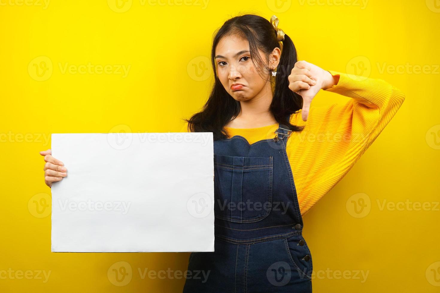 Mujer joven bonita y linda aversión, triste, mano sosteniendo pancarta vacía en blanco, cartel, tablero blanco, tablero de letrero en blanco, tablero de anuncio blanco, presentando algo en el espacio de la copia, promoción foto