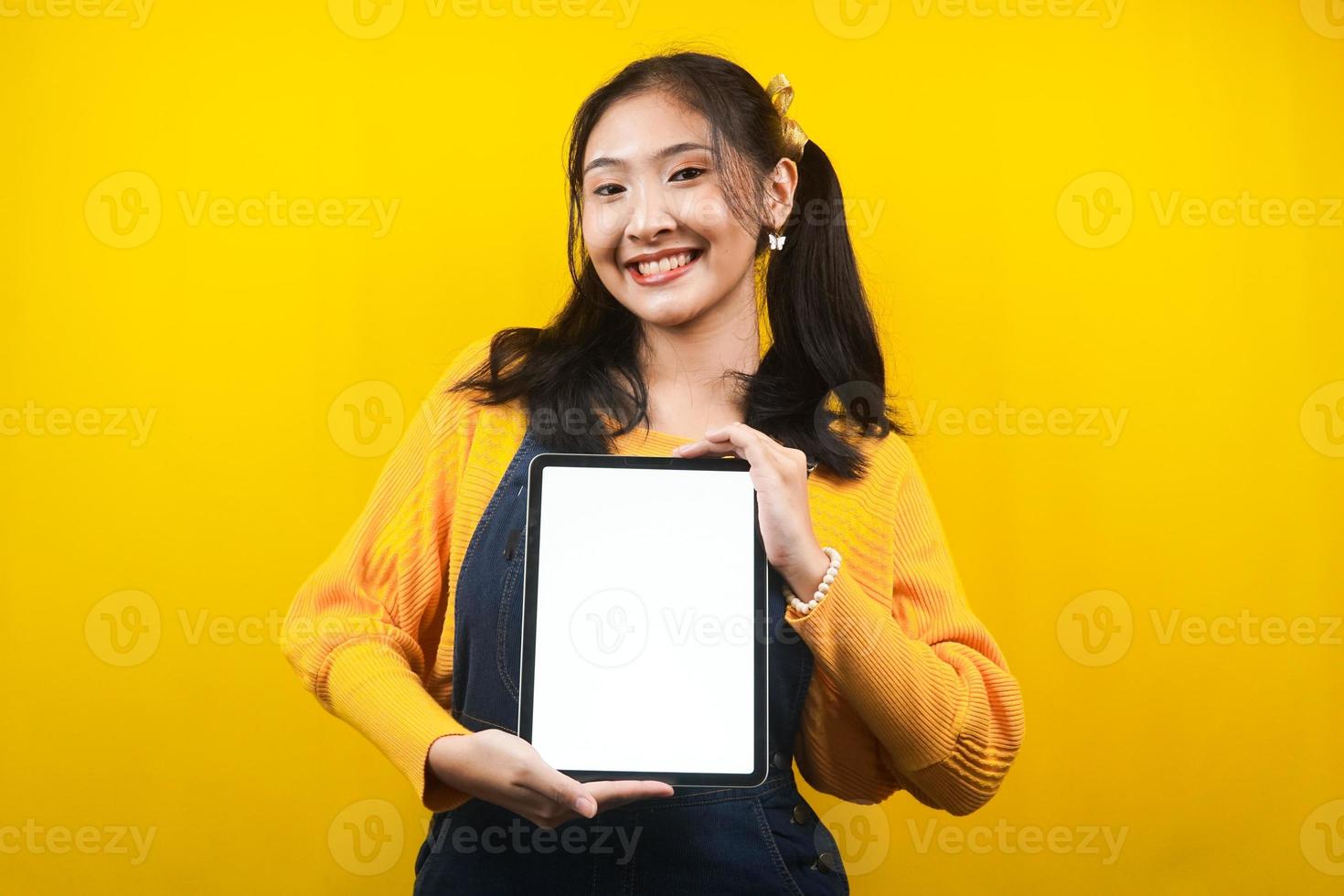 Bonita y linda mujer joven alegre, confiada, con las manos sosteniendo la tableta, con la tableta de pantalla en blanco o en blanco, presentando algo, promocionando un producto, publicidad, aislado foto