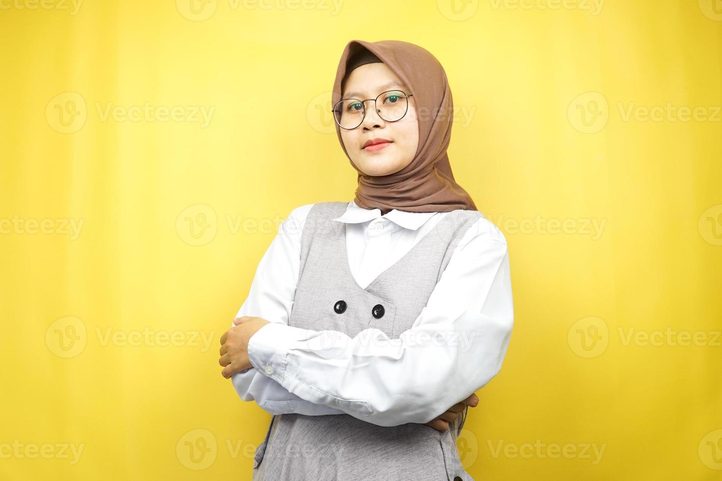 Beautiful young asian muslim woman smiling confidently with arms outstretched facing the camera isolated on yellow background photo