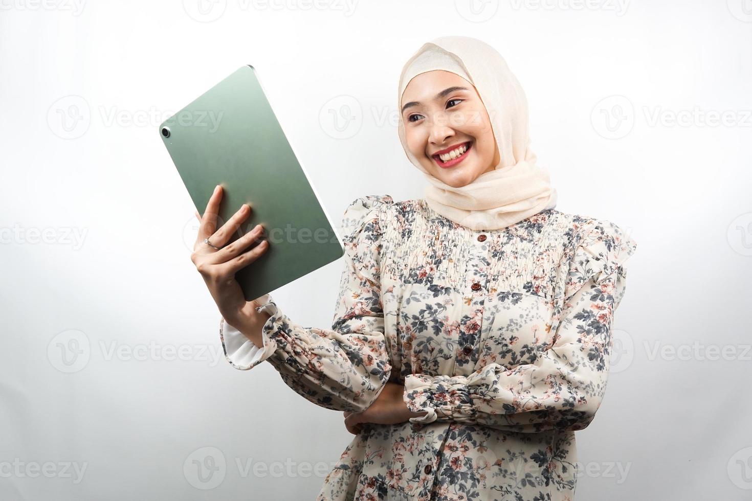 Hermosa joven mujer musulmana asiática sonriendo, emocionada y alegre celebración de tableta, aislado sobre fondo blanco. foto