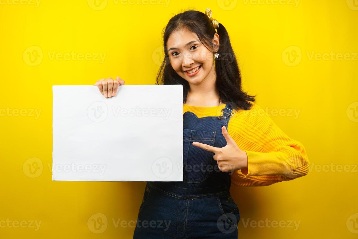 Bonita y linda mujer joven alegre sosteniendo pancarta vacía en blanco, cartel, tablero blanco, tablero de letrero en blanco, tablero de anuncio blanco, presentando algo en el espacio de la copia, promoción foto