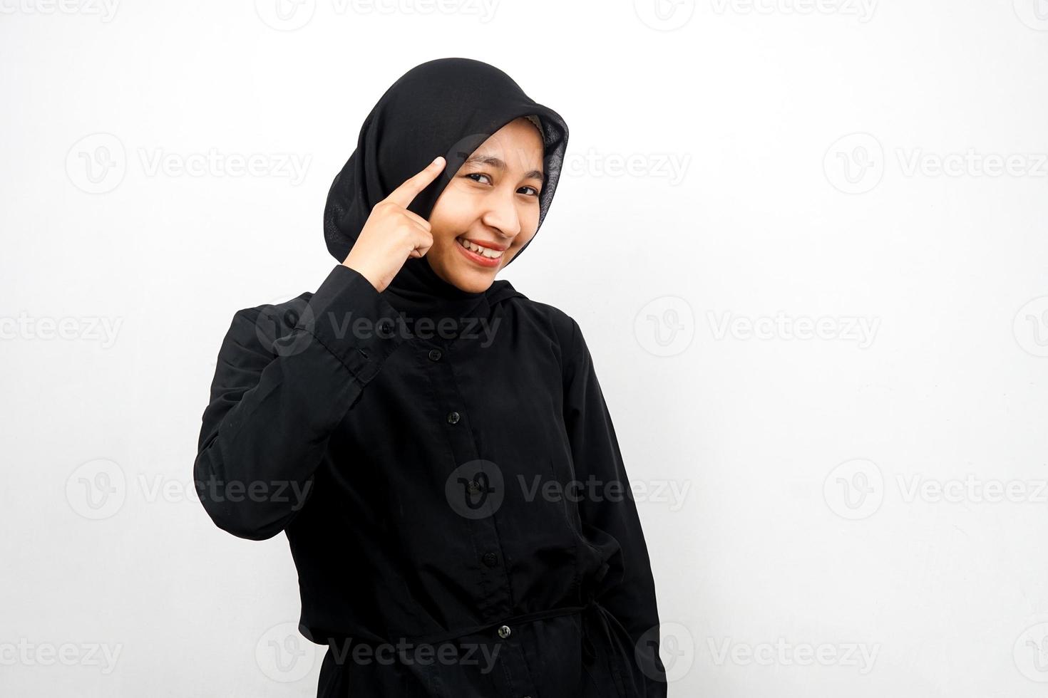 Beautiful young asian muslim woman with finger pointing at head, thinking smart, isolated on white background photo