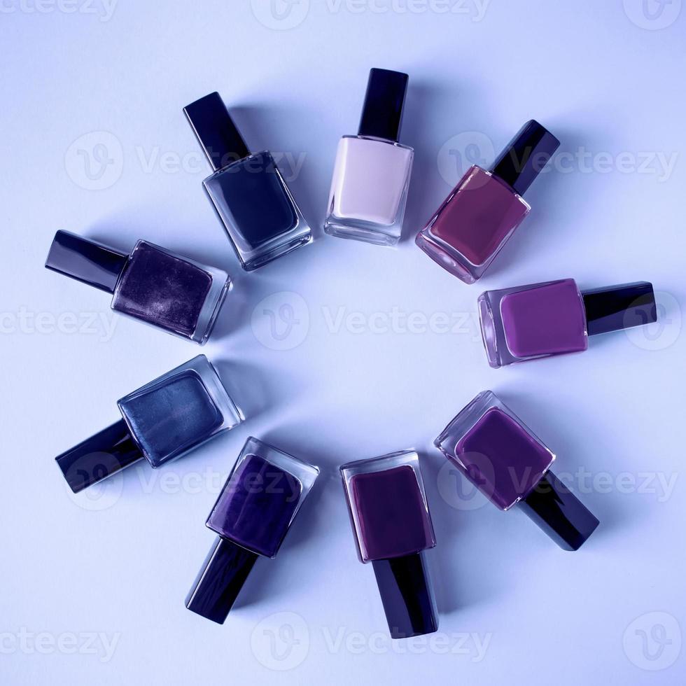 Group of bright colored nail polishes on purple background. Trendy color of the year 2022. photo