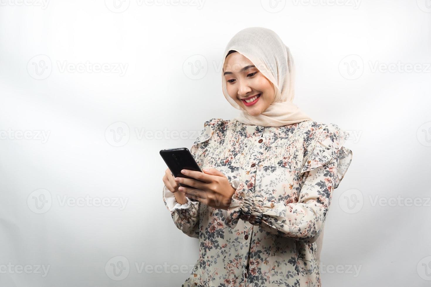 Hermosa joven mujer musulmana asiática sonriendo con confianza sosteniendo smartphone aislado sobre fondo blanco, concepto de publicidad foto