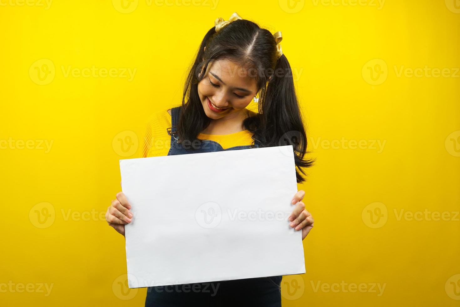 Bonita y linda mujer joven alegre sosteniendo pancarta vacía en blanco, cartel, tablero blanco, tablero de letrero en blanco, tablero de anuncio blanco, presentando algo en el espacio de la copia, promoción foto