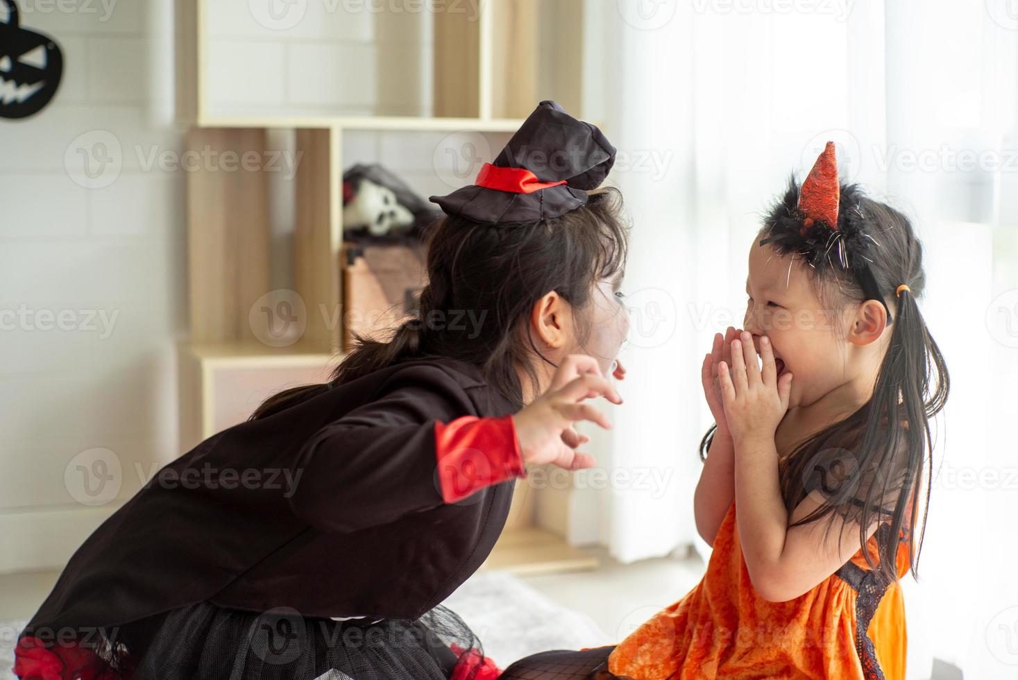 Retrato de dos hermanas en disfraces de halloween actuando como una expresión de frigthening fantasma el uno al otro en el festival de halloween foto