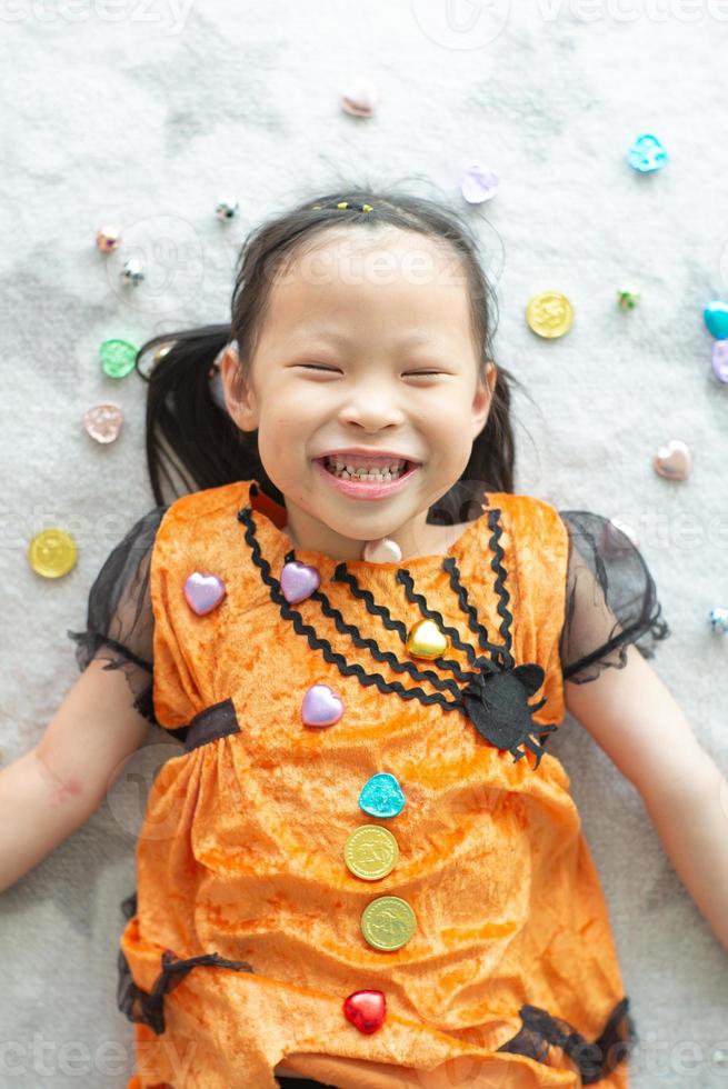 Retrato de niña asiática arrojar y comer dulces y chocolate de trick or treat con tema de halloween en segundo plano. foto
