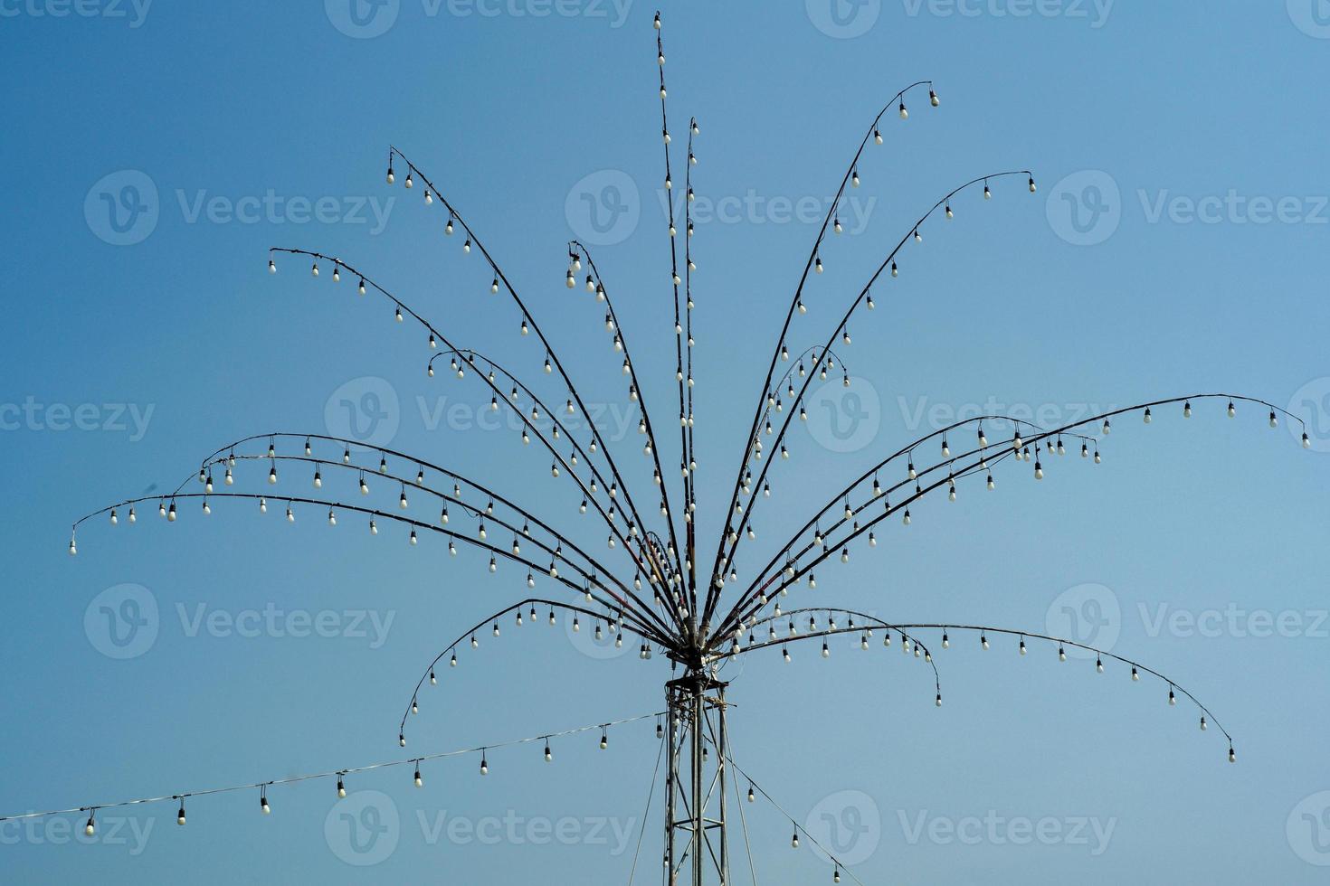 Many bulbs decorated on the steel branches in the shape of flower for local festival in Thailand isolated on blue sky background photo