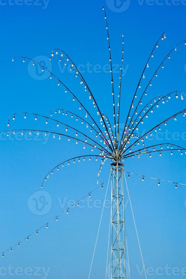 Many bulbs decorated on the steel branches in the shape of flower for local festival in Thailand isolated on blue sky background photo