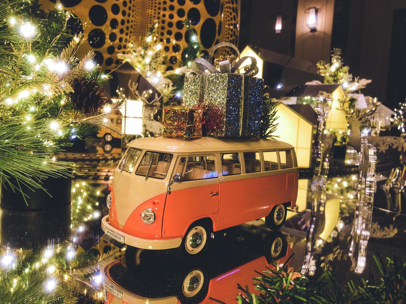 composición de año nuevo. Juguete de autobús naranja con regalos y el árbol de navidad en el fondo foto