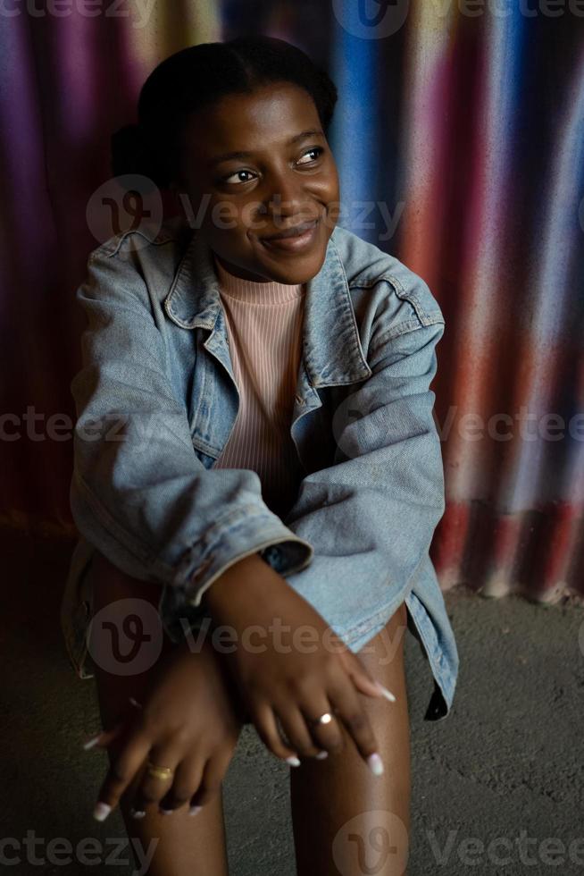 Retrato de mujer joven sonriente con peinado afro mirando hacia los lados. foto