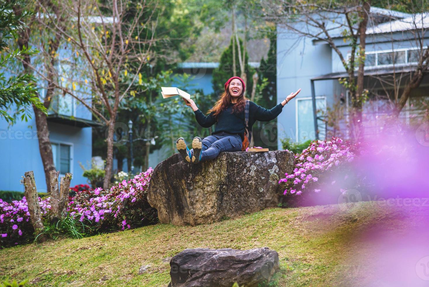 mujer viaje naturaleza en el jardín de flores. relájese sentado en las rocas y leyendo libros en medio de la naturaleza en doi inthanon. foto