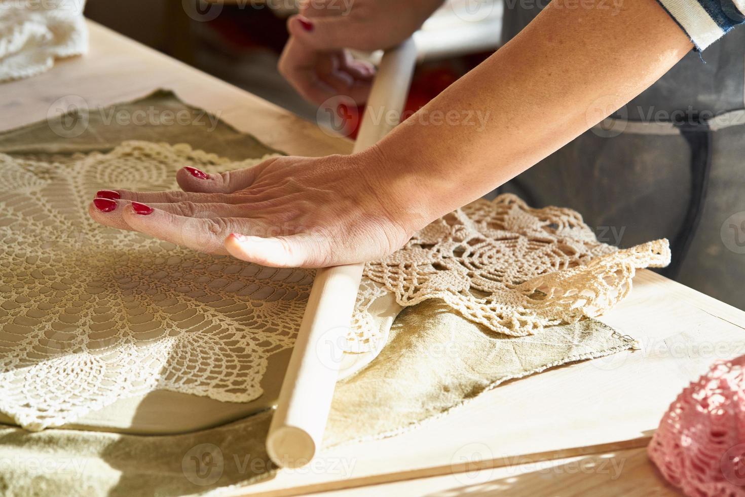 Mujer haciendo patrón en placa de cerámica, manos de cerca, se centran en las palmas de las manos con arcilla foto