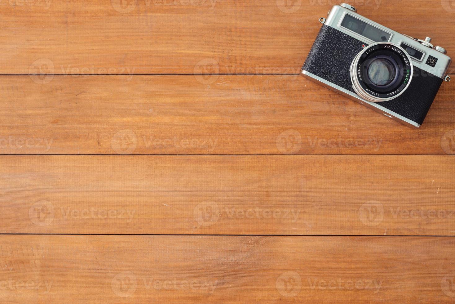 Office desk wooden table with old camera. Top view with copy space. Top view of old camera over wooden table. Retro vintage filter. photo