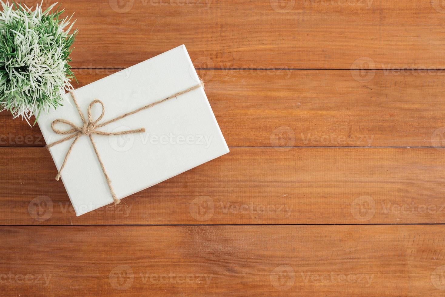 Christmas and New Year holidays gift box wrapped with white paper and ribbon bow on wood table - top view on wooden table top background. photo