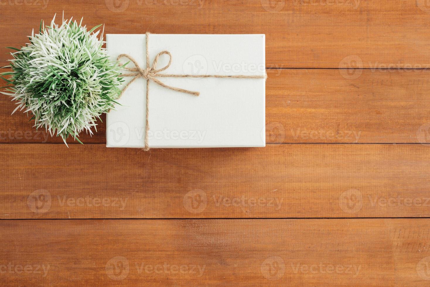 Christmas and New Year holidays gift box wrapped with white paper and ribbon bow on wood table - top view on wooden table top background. photo