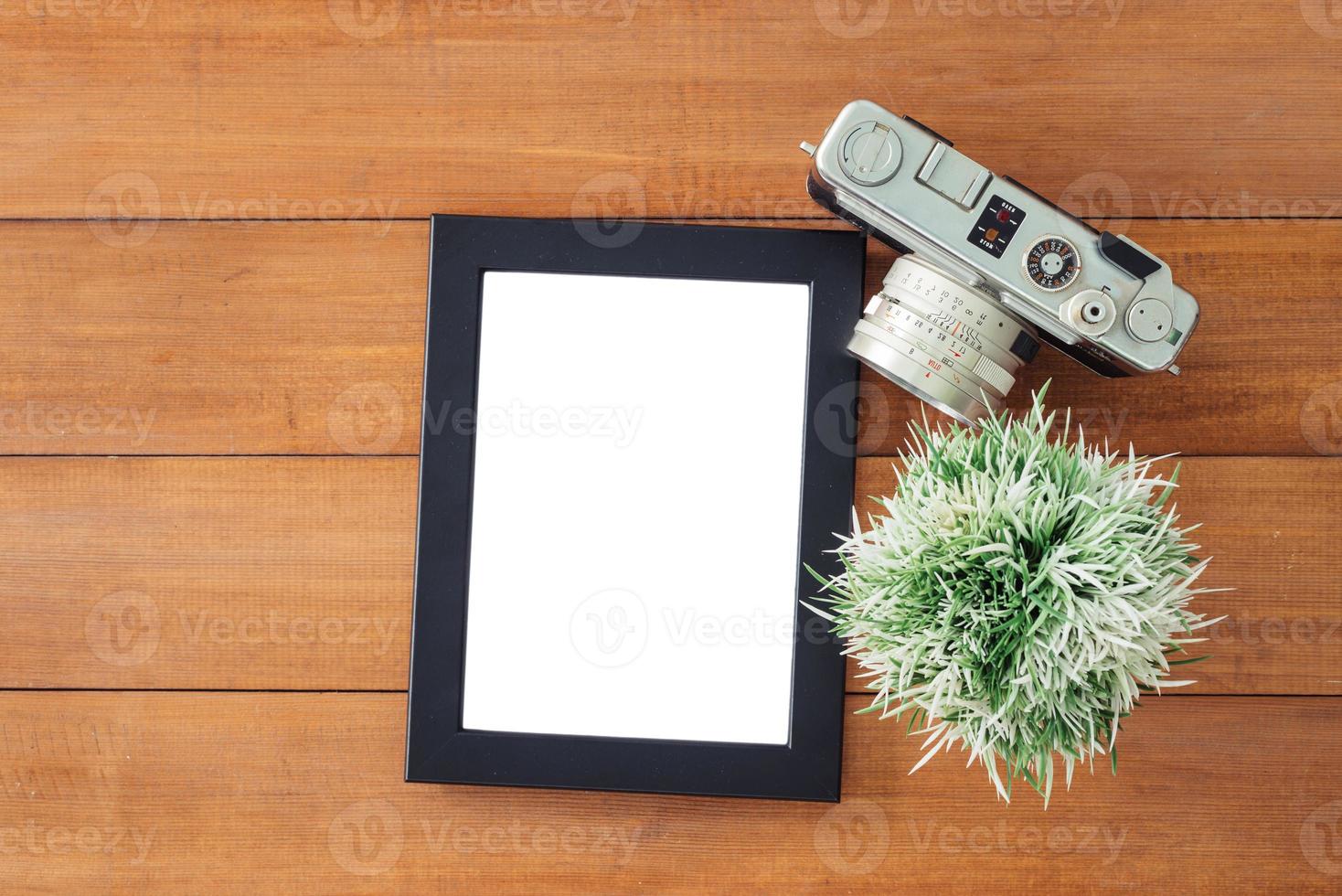 Creative flat lay photo of workspace desk. Office desk wooden table with old camera and poster mockup template. Top view with copy space. Top view of old camera over wooden table. Retro vintage filter